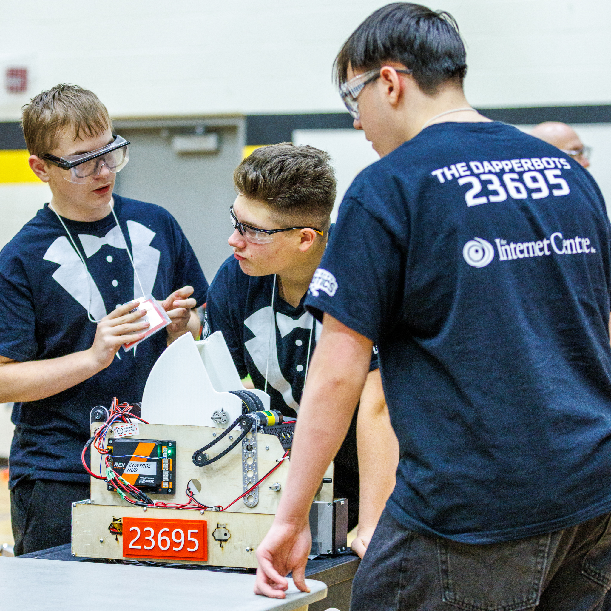 The Dapperbots in their tuxedo shirts working on their robot